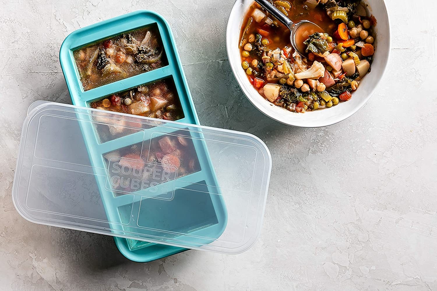 Full frozen souper cube on table next to bowl of soup