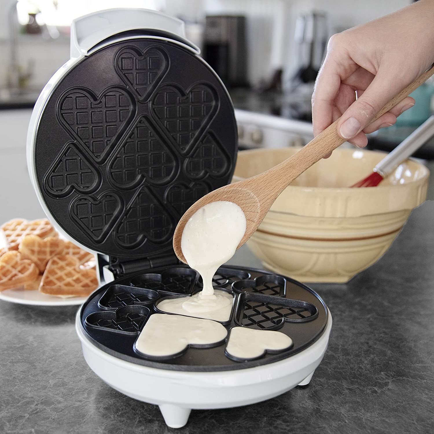 A person pouring batter into the waffle maker 