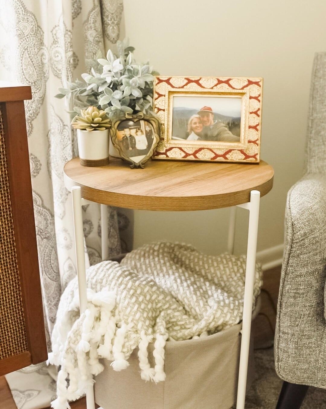 reviewer pic of the round side table with wood top, grey fabric basket at the bottom and white legs