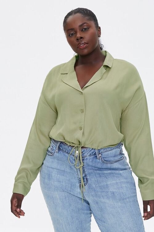 Model wears the olive green drawstring-hem top with light wash jeans