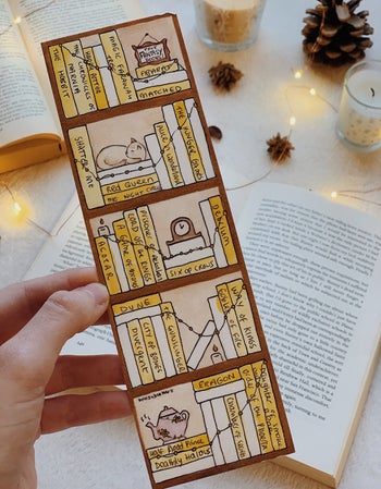 person holding the bookmark after coloring it and writing in the name of finished books