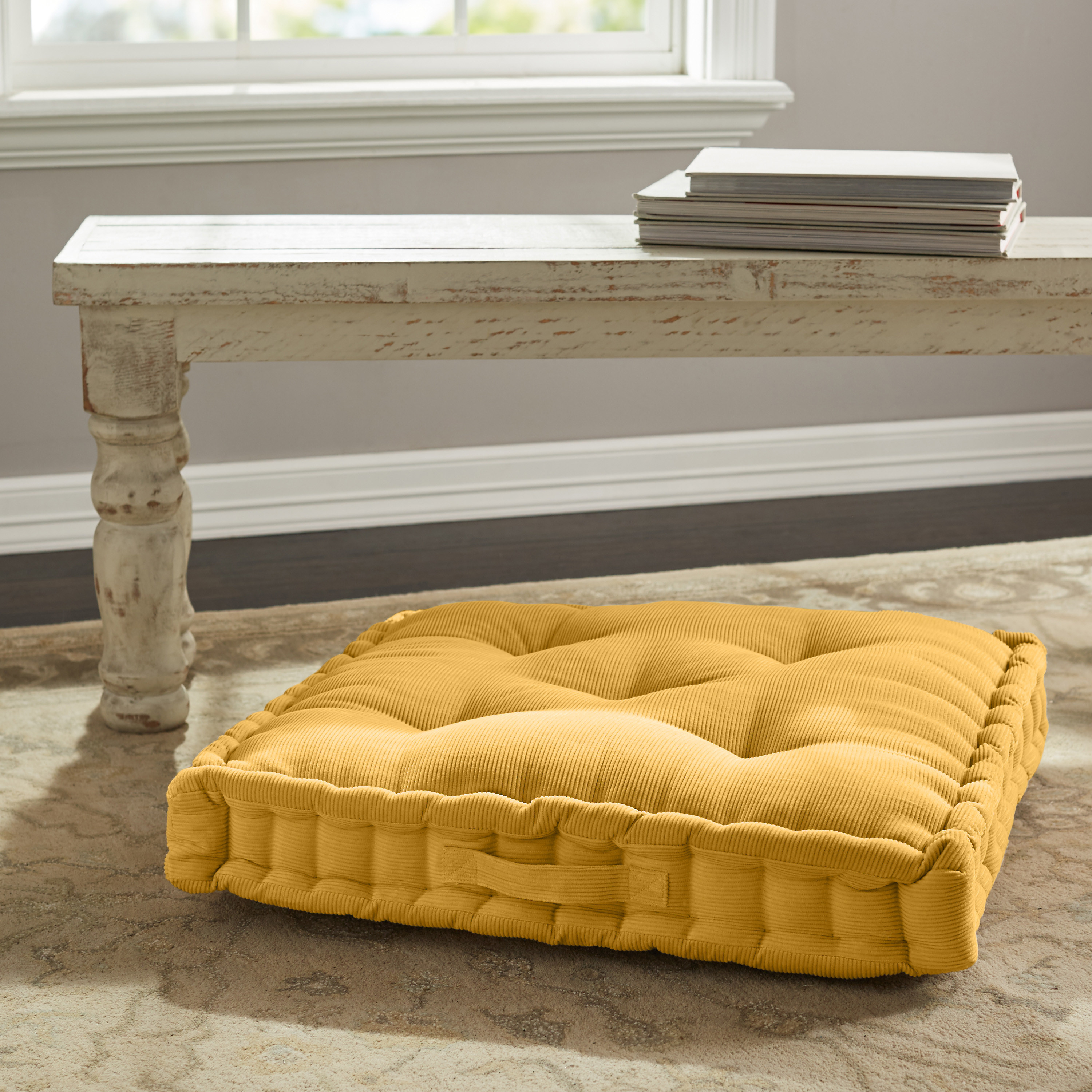 a mustard yellow tuft floor pillow on a floor