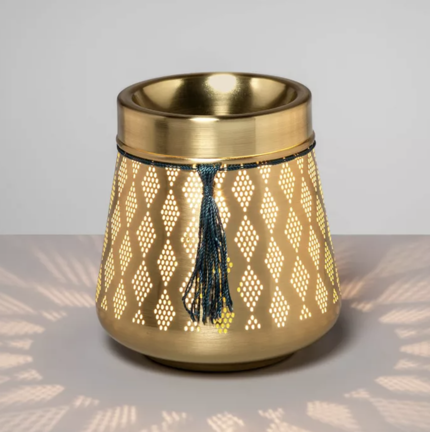 The gold wax melter which has a punched design and tassel accent