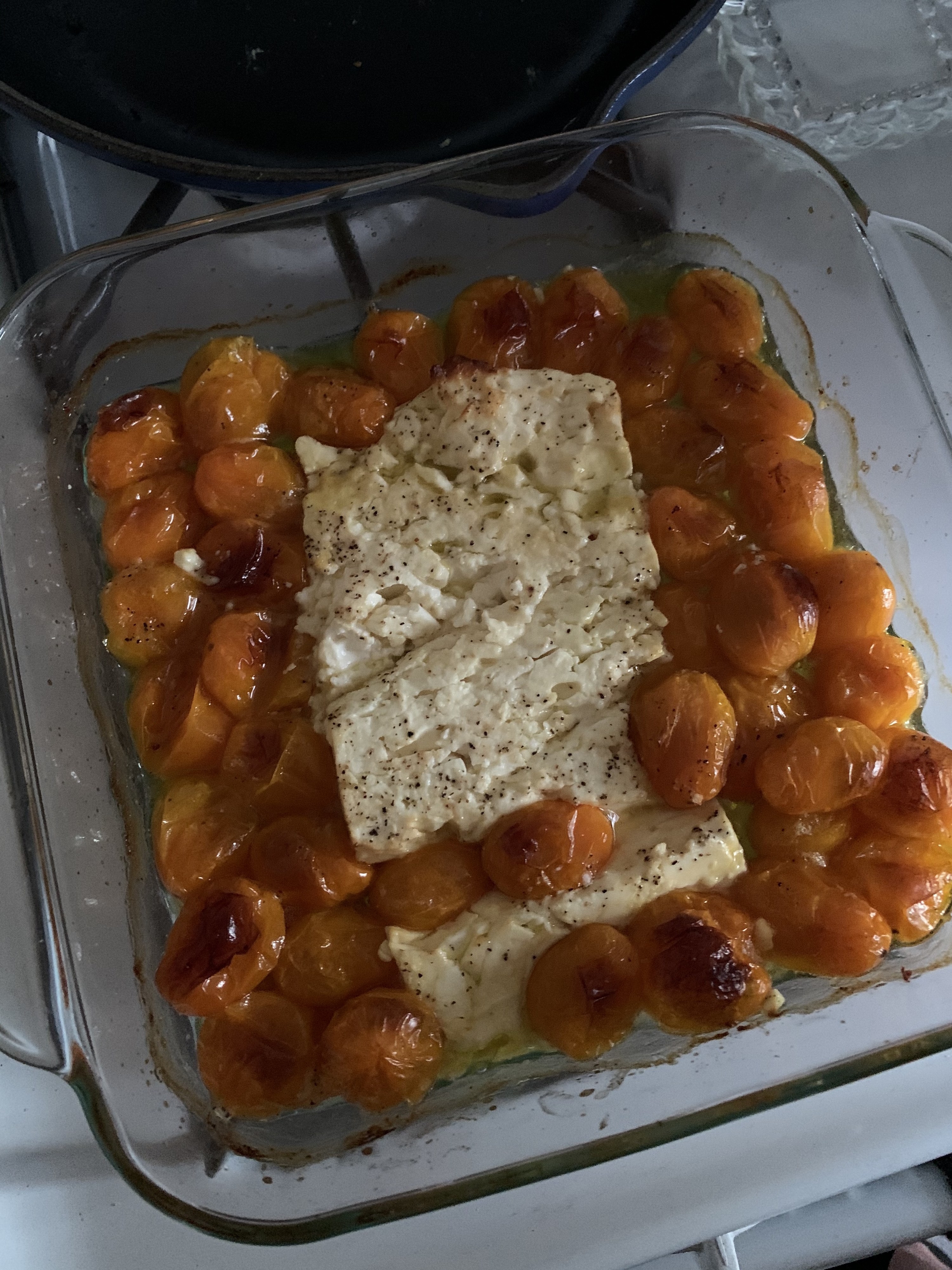 An image of baked feta cheese with tomatoes just out of the oven