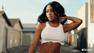 GIF of Normani flipping her hair while walking down the street 
