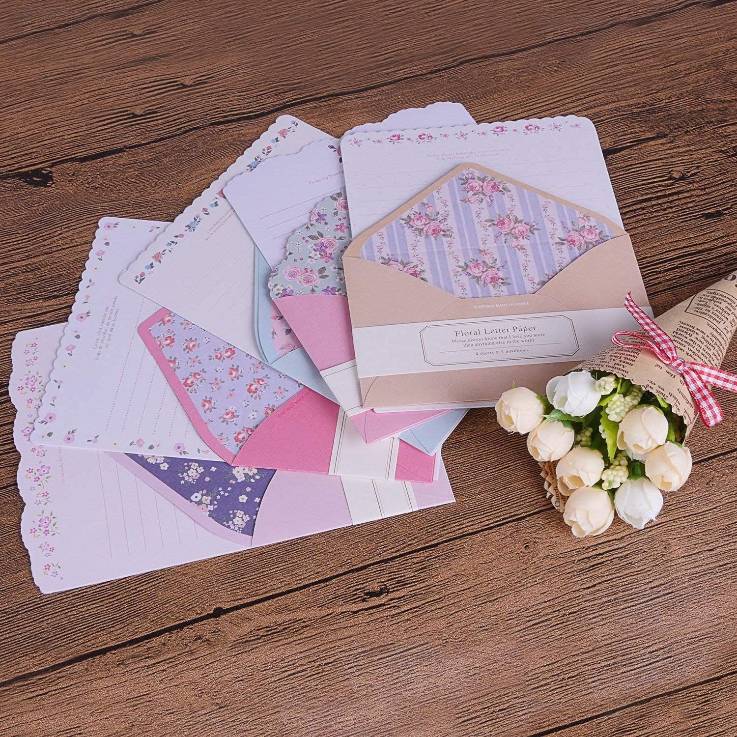 Envelopes with cute paper sticking out of them next to a bundle of roses