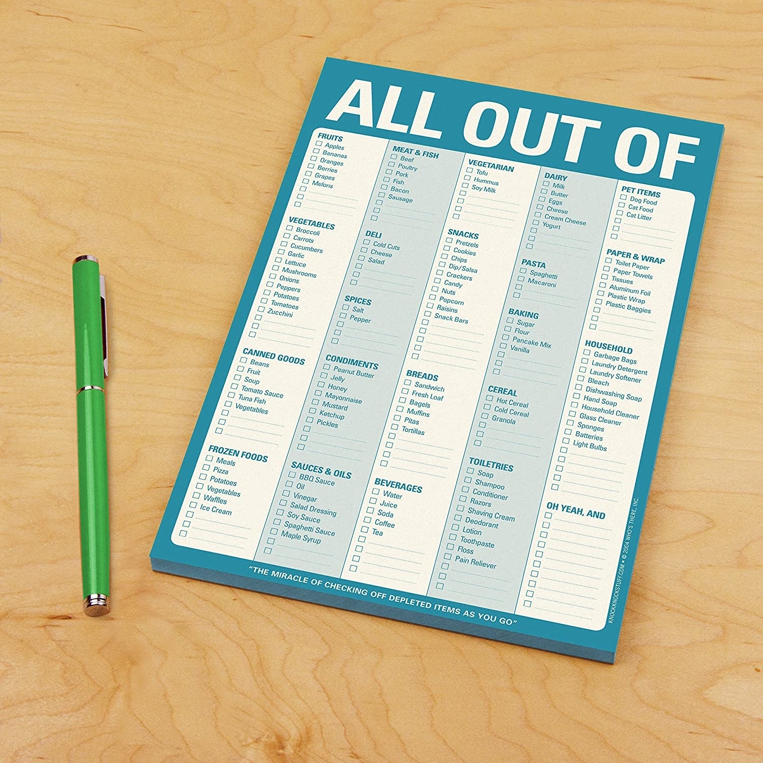 Note pad on wood table next to green pen