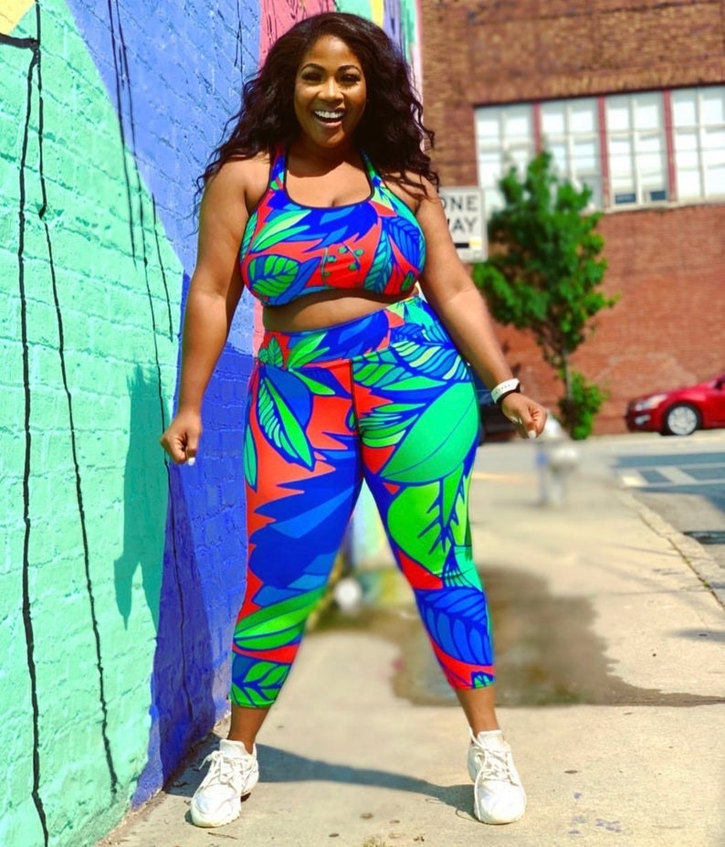 Model wears tropical flower-printed red, blue, and green high-rise workout leggings 