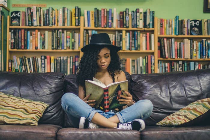 A young woman reads a book on a couch.