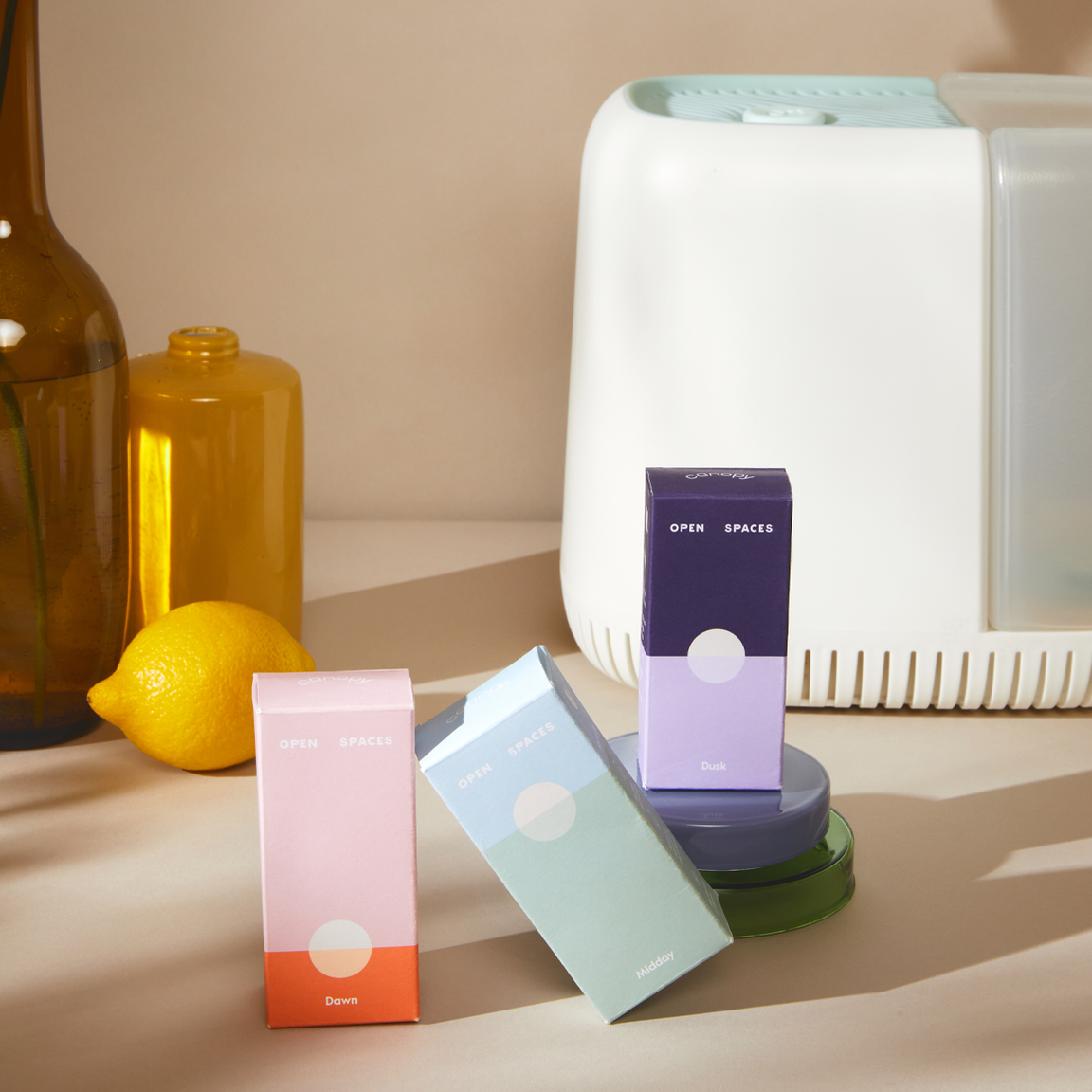 the white rectangle humidifier with three small fragrance boxes in pink, blue, and purple sitting in front of it