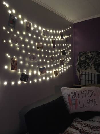 reviewer pic of the string lights hanging on a wall with photos in them
