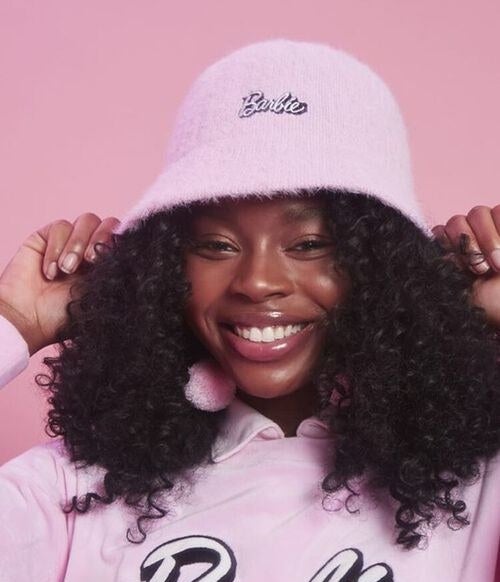 Model wears the pink bucket hat with black and pink barbie embroidery