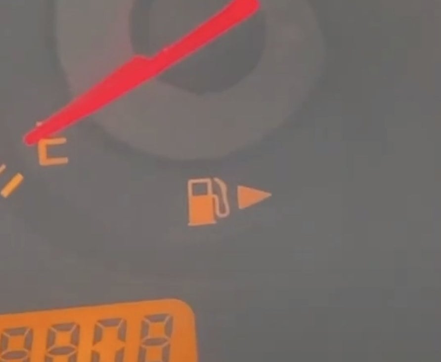 A gas tank symbol on a car dashboard features an arrow pointing to the right