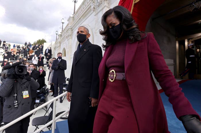 Michelle, wearing a knitted top with matching pants, belt, and long coat descends the stairs at President Joe Biden&#x27;s inauguration along with Barack Obama 