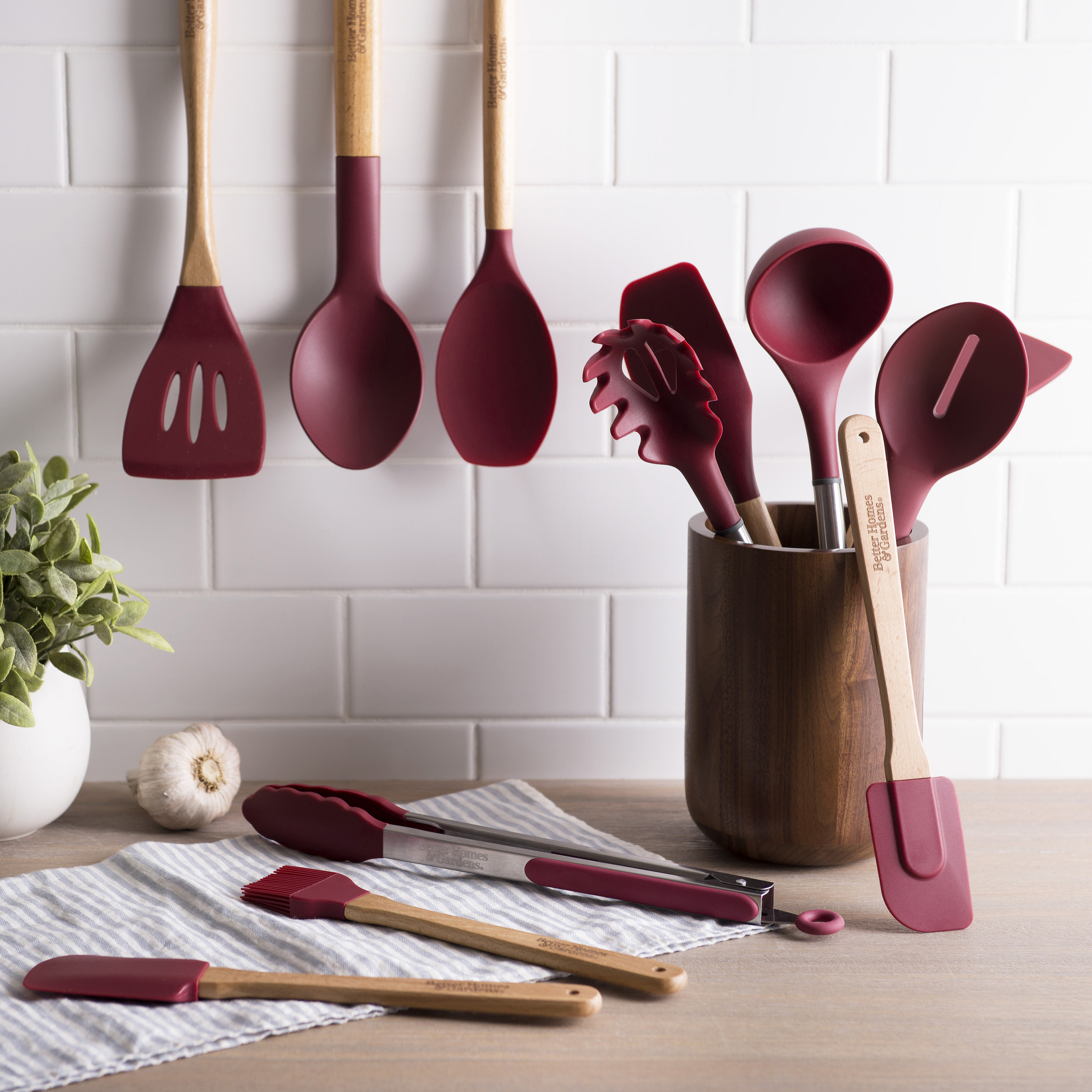merlot colored silicon kitchen utensils laying on a table, in a canister, and hanging on a wall