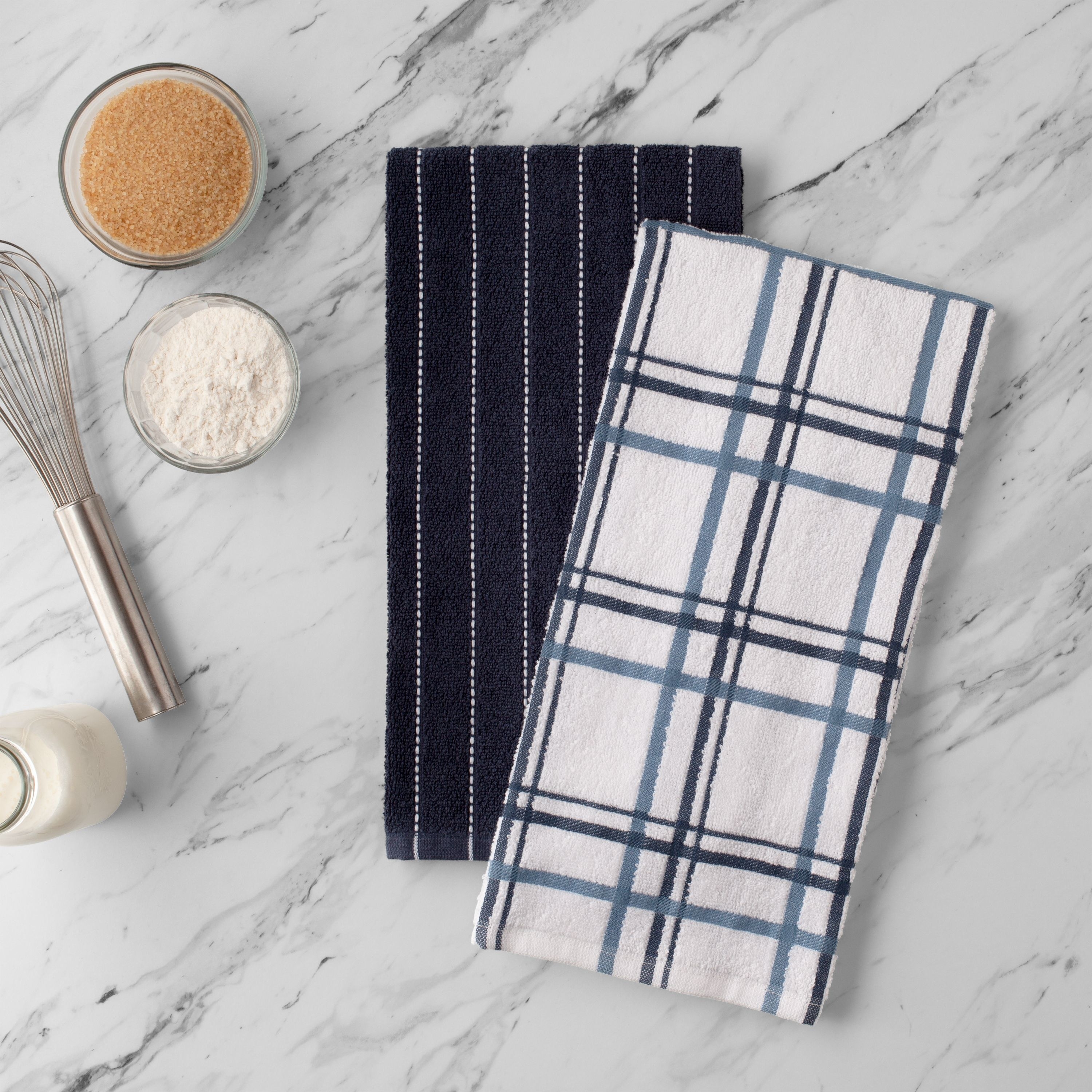 two dish towels with navy blue designs on a table