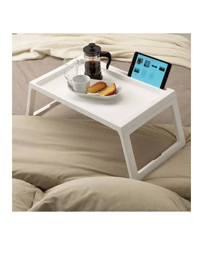 A white table on a bed with food on it