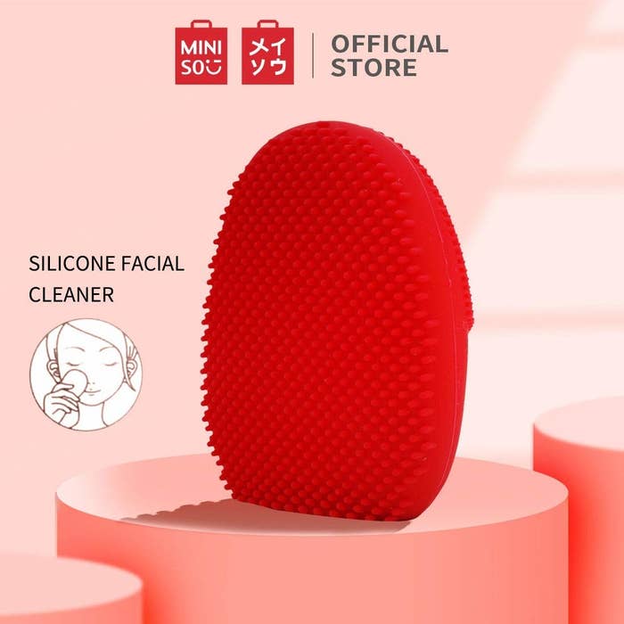 A red massage brush on a pink surface 