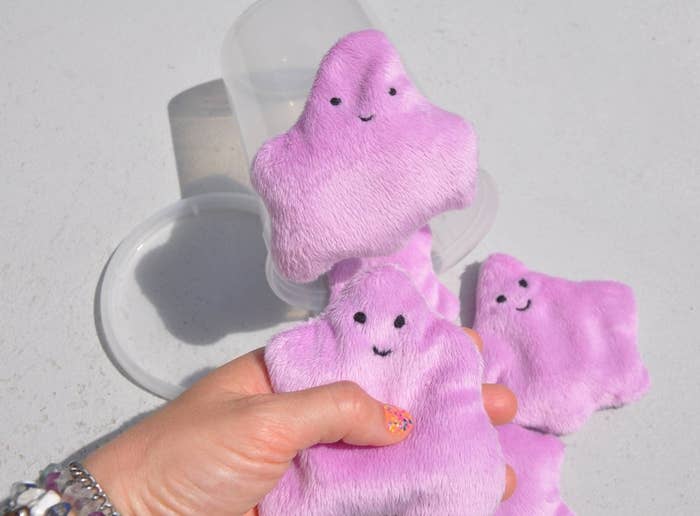 a hand squeezing the lavender slime plushie 