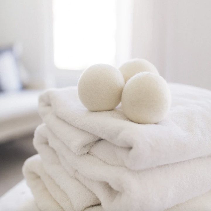 Three wool dryer balls on top of stack of towels