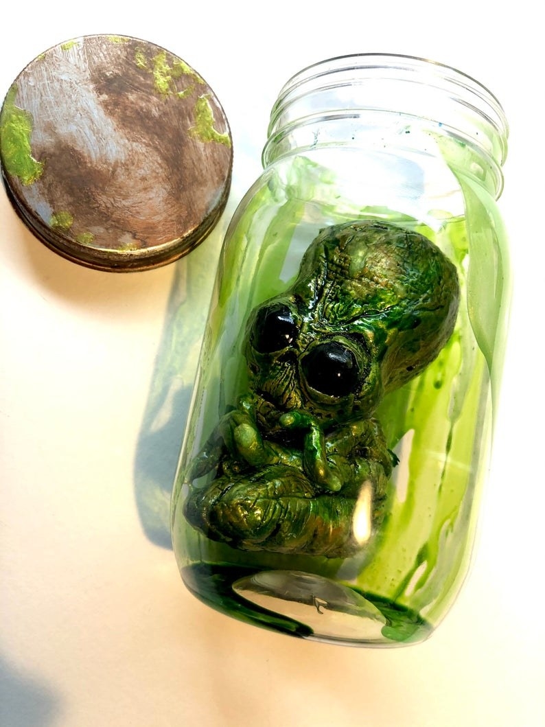 the alien doll in a glass jar with green slime