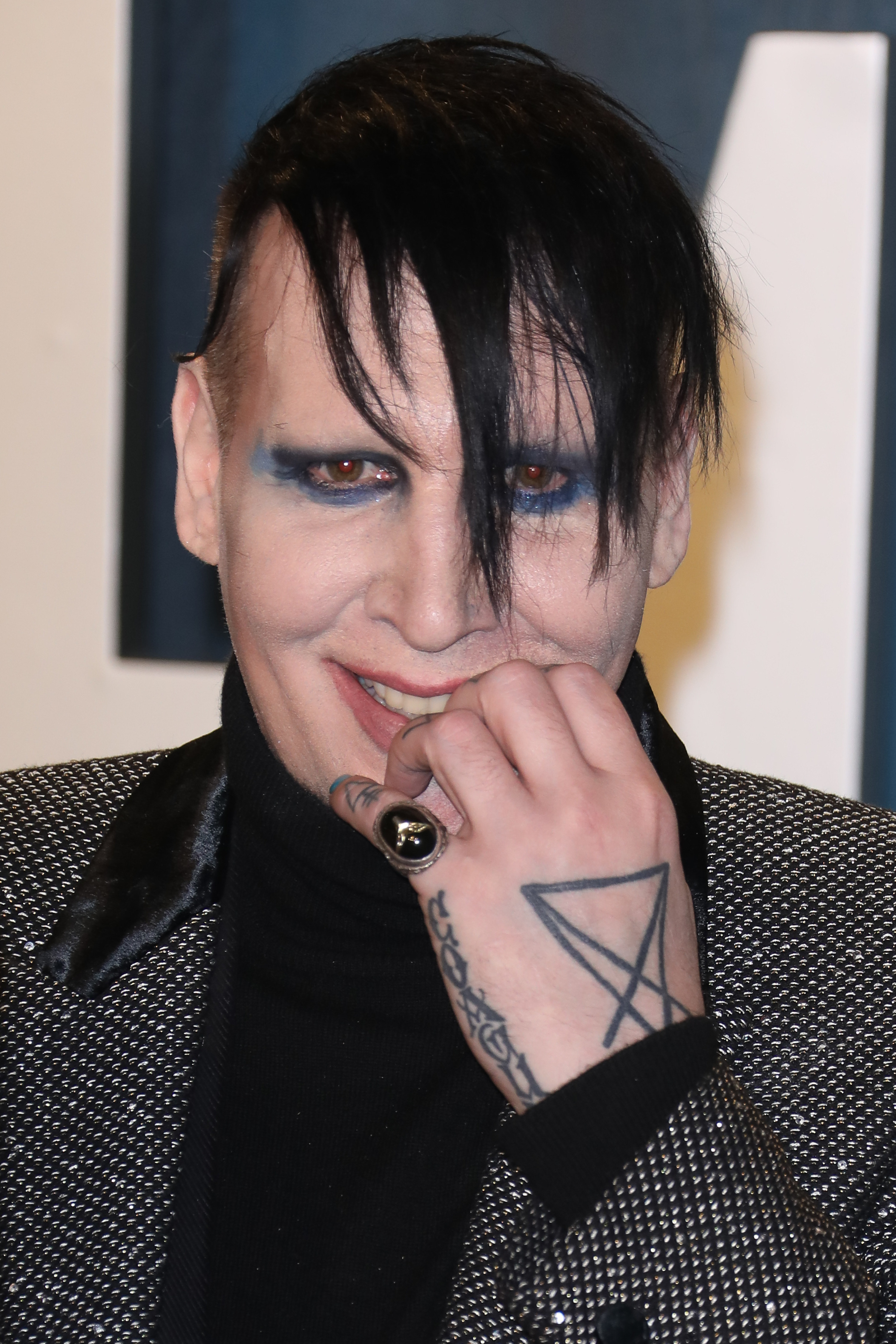 Marilyn Manson with his hand in front of his mouth at the Vanity Fair Oscar Party