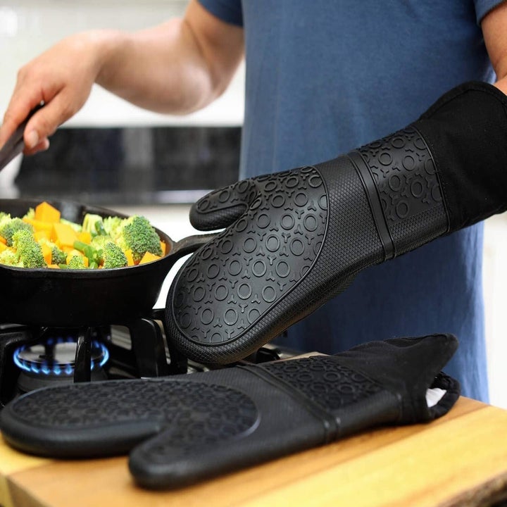 Model wearing black silicone oven mitt while cooking