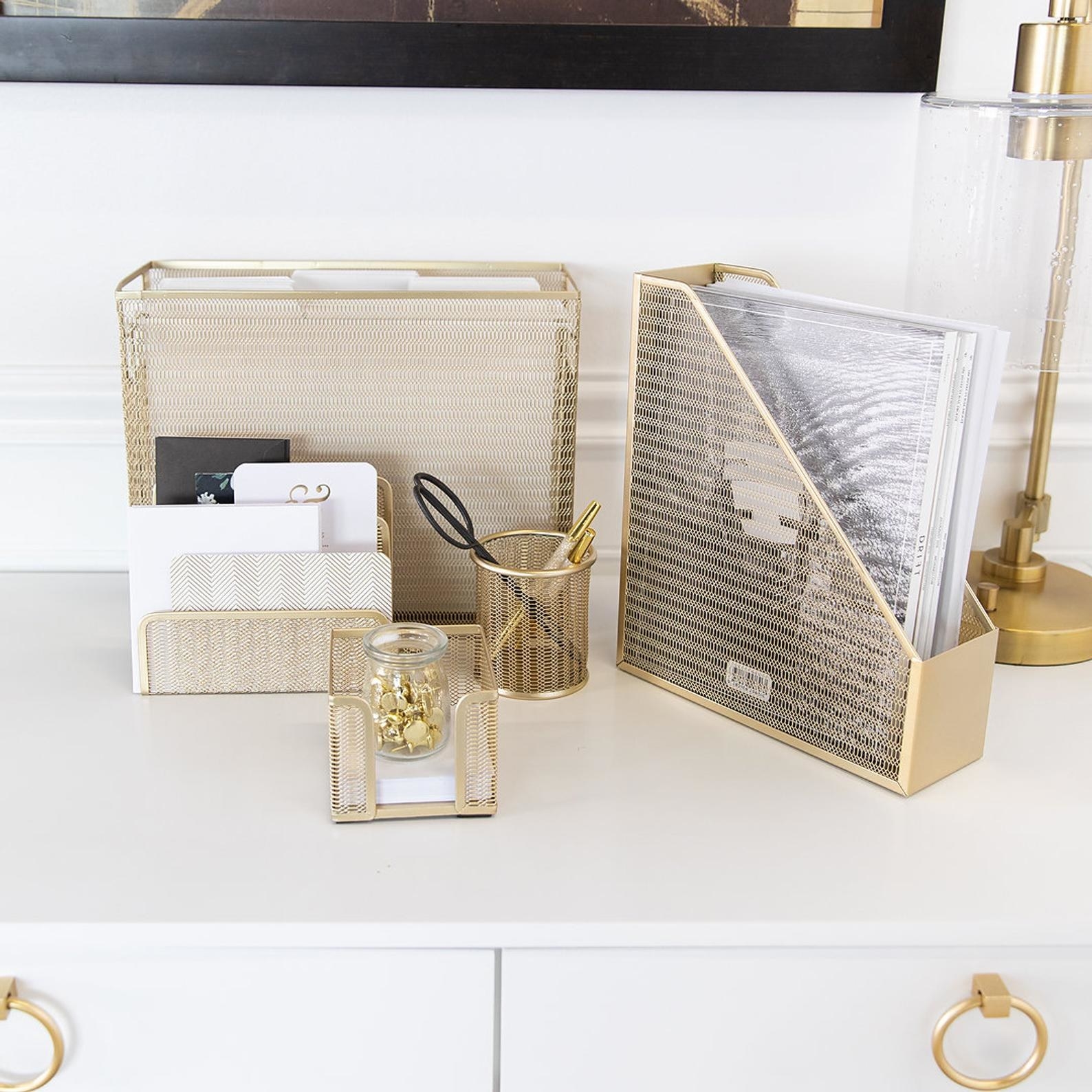 Five gold desk organizers filled with supplies and placed on desk