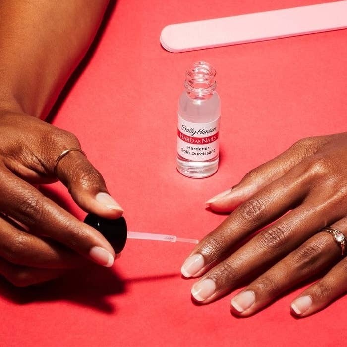 A person applying the nail hardener to their nails