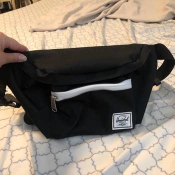 A reviewer photo of a black Herschel waist pack with a front zip pocket 