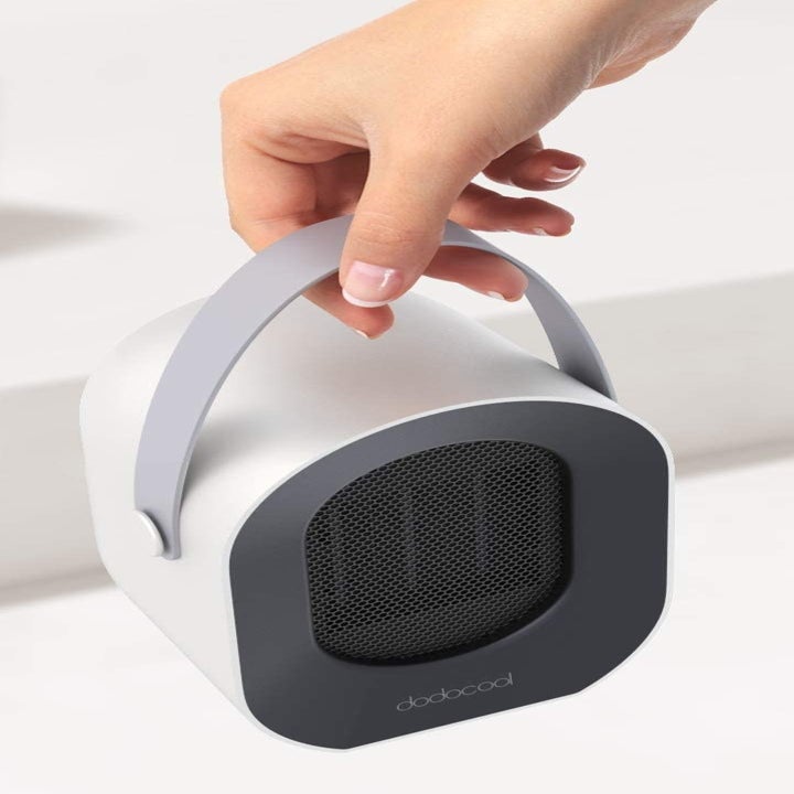 A hand holding the heater by its portable handle