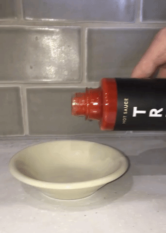 Gif of the writer pouring some of the Original TRUFF sauce into a dish to show its consistency and color