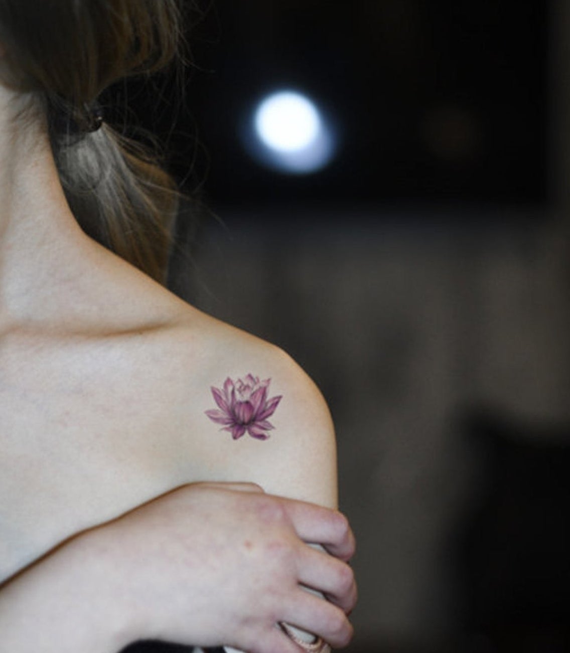 Model with a small purple lotus design on their shoulder
