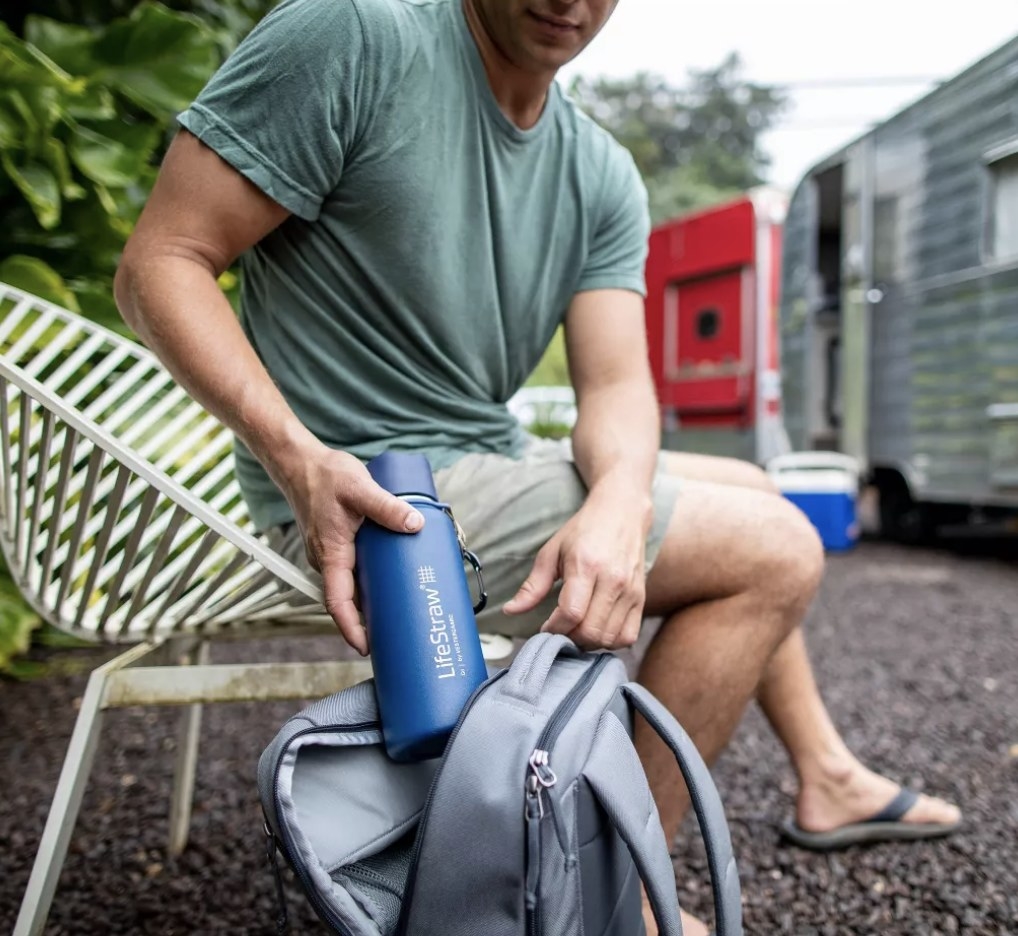 Person pulling a blue water bottle out of a backpack
