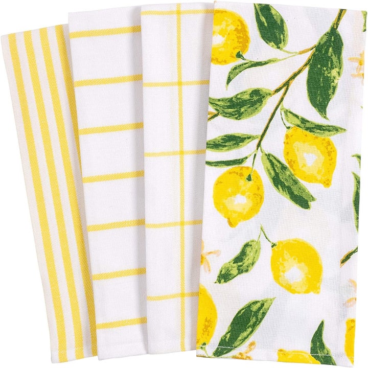 four towels: one with yellow and green lemon and branch illustrations, three white with yellow grid or stripes