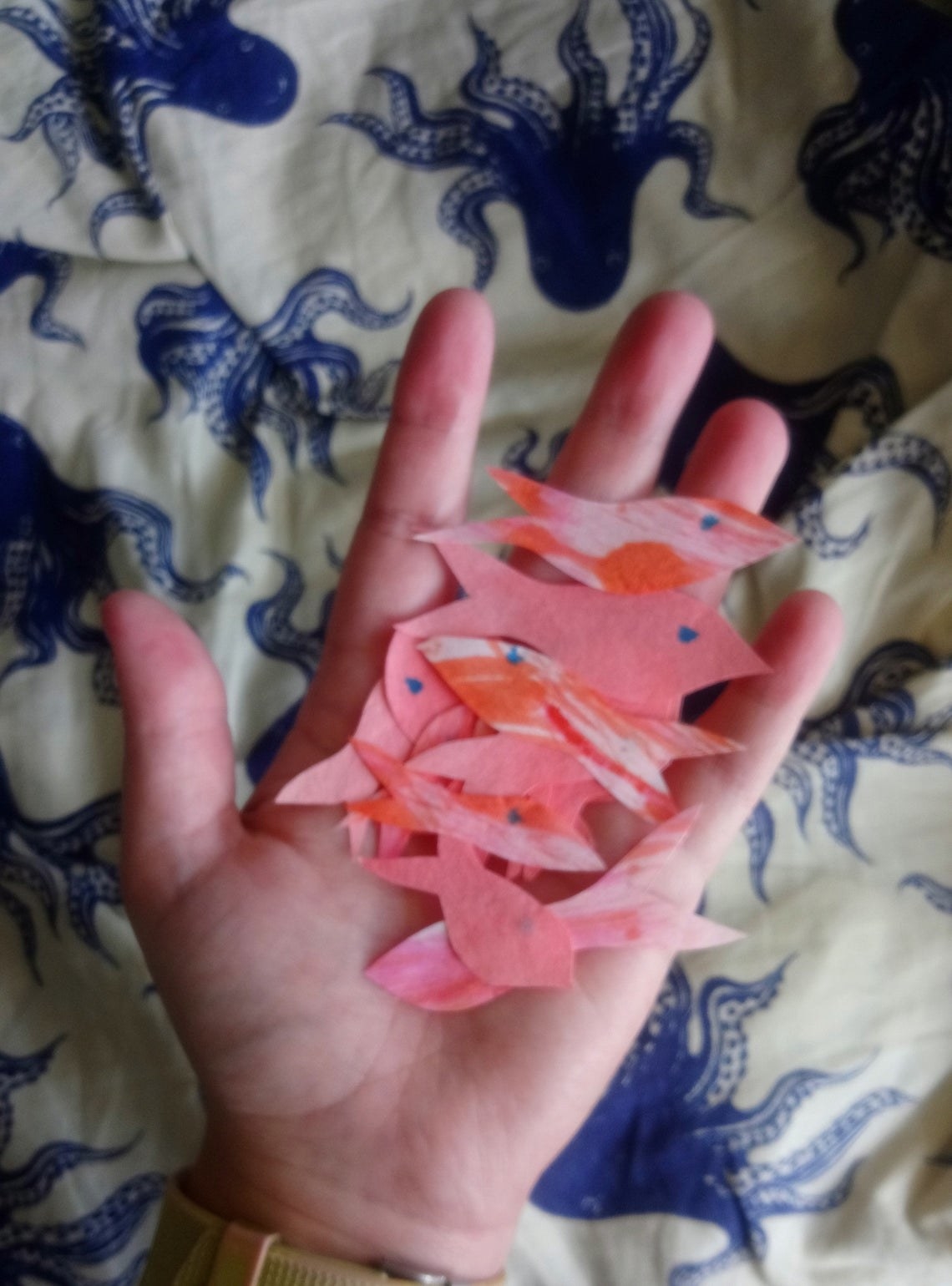 hands holds what looks like hand cut paper fish 