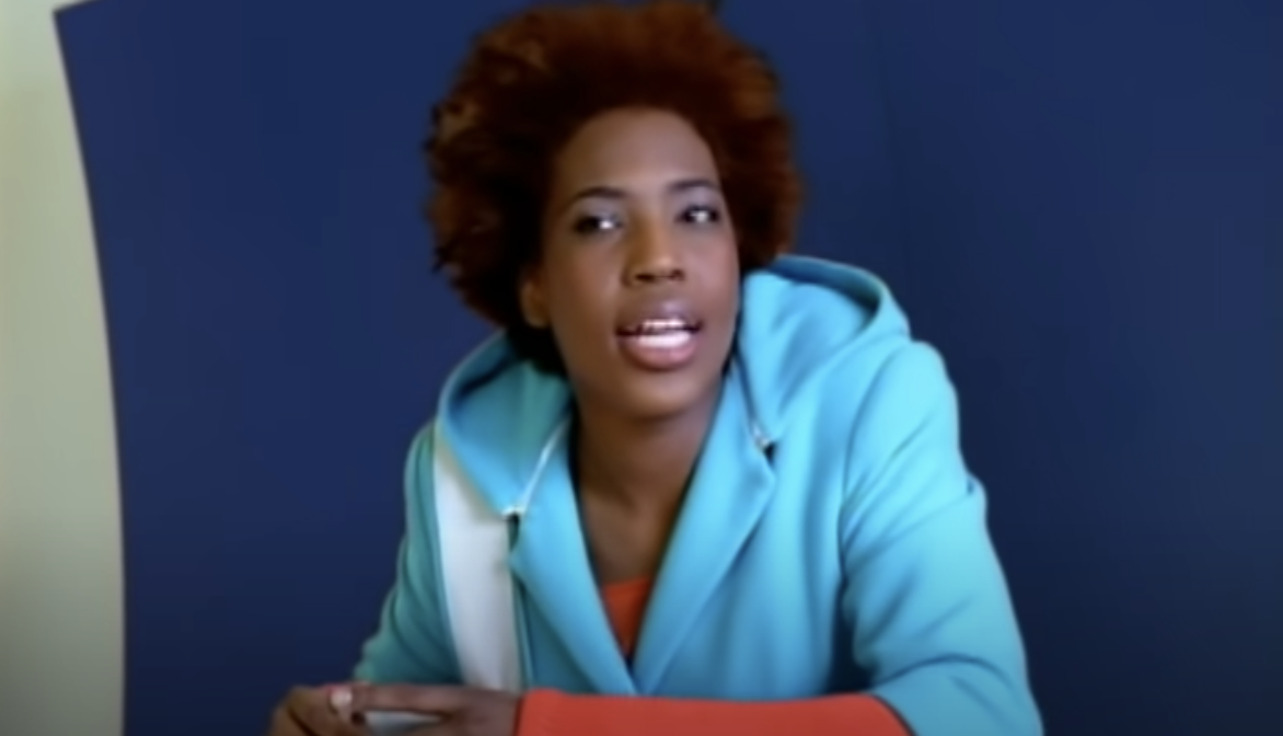 Macy Gray sitting at a table and singing in the "I Try" music video