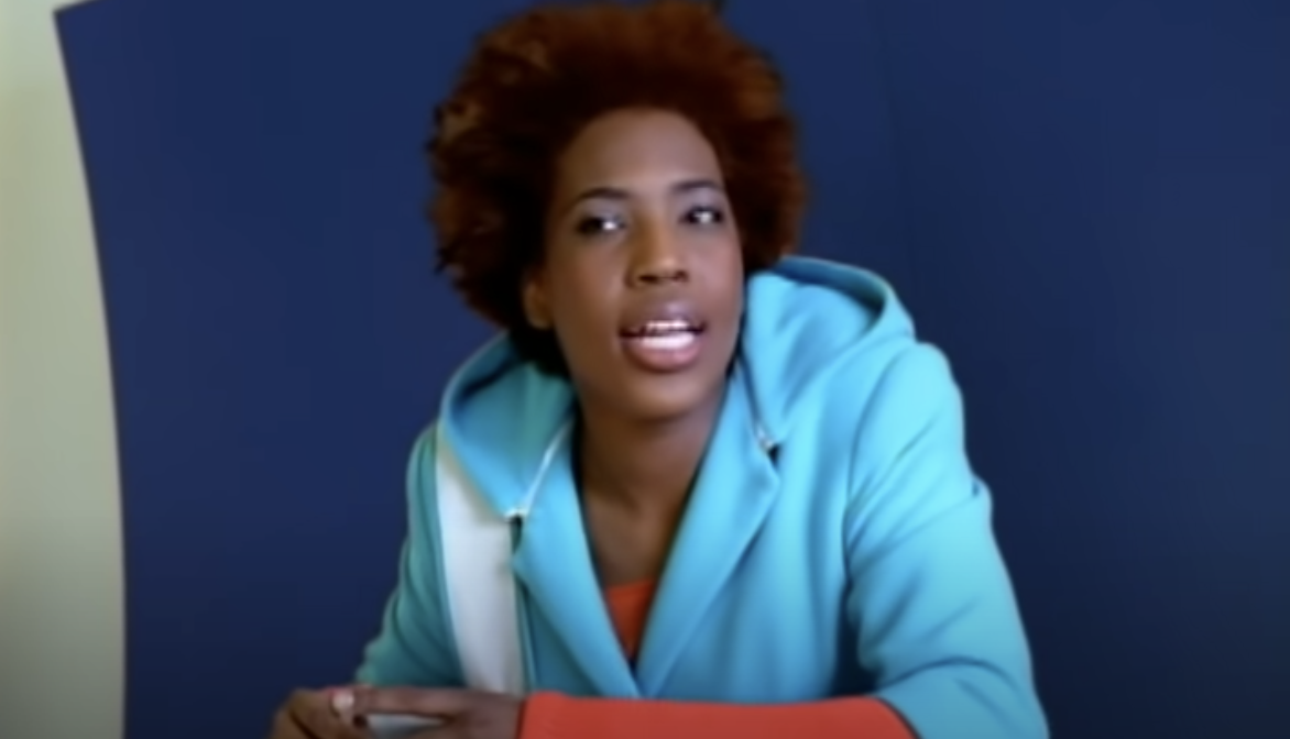 Macy Gray sitting at a table and singing in the &quot;I Try&quot; music video