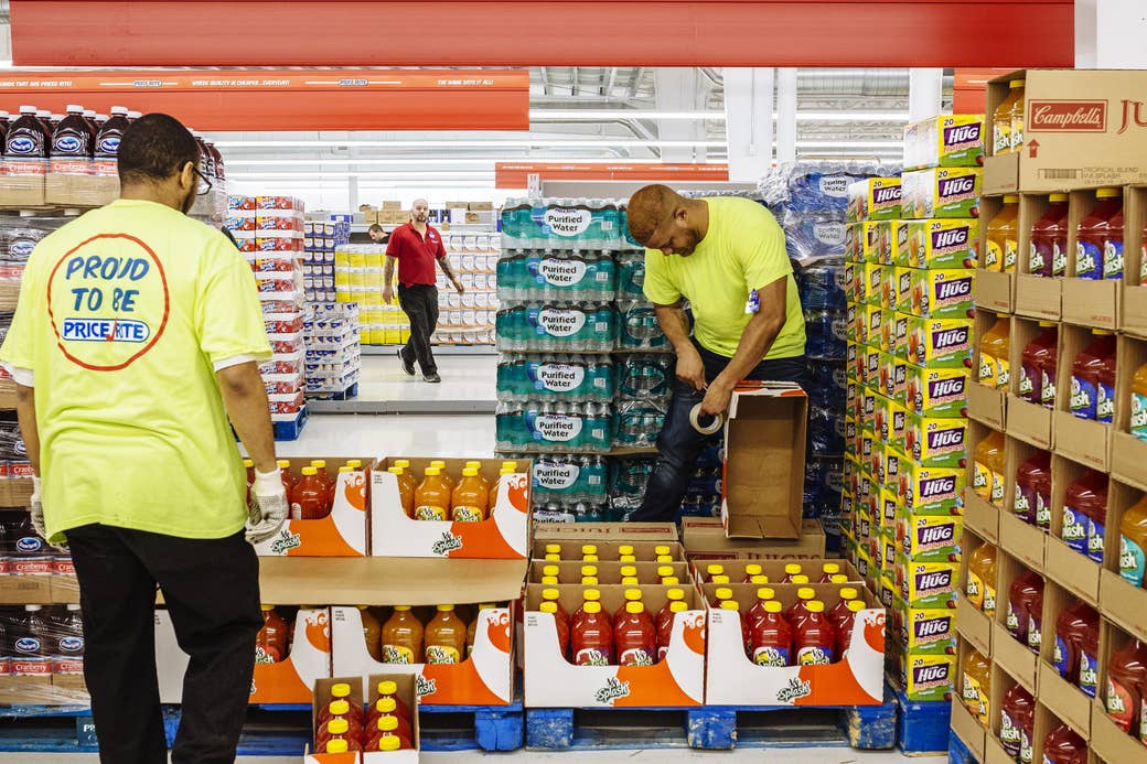 Two men in neon Price Rite shirts set up a display of juice bottles inside the supermarket