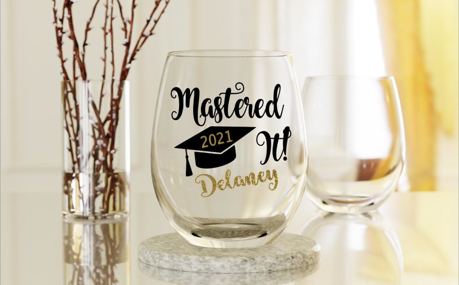 stemless wine glass that reads &quot;mastered it delaney&quot; with 2021 inside a graphic of a graduation cap