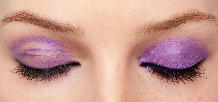 A model wearing the primer on their right eye, and not wearing the primer on the left eye, showing how the primer kept their purple eyeshadow in place.