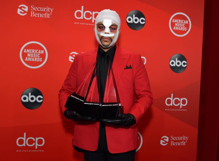 The Weeknd poses in face bandages while holding awards at the American Music Awards