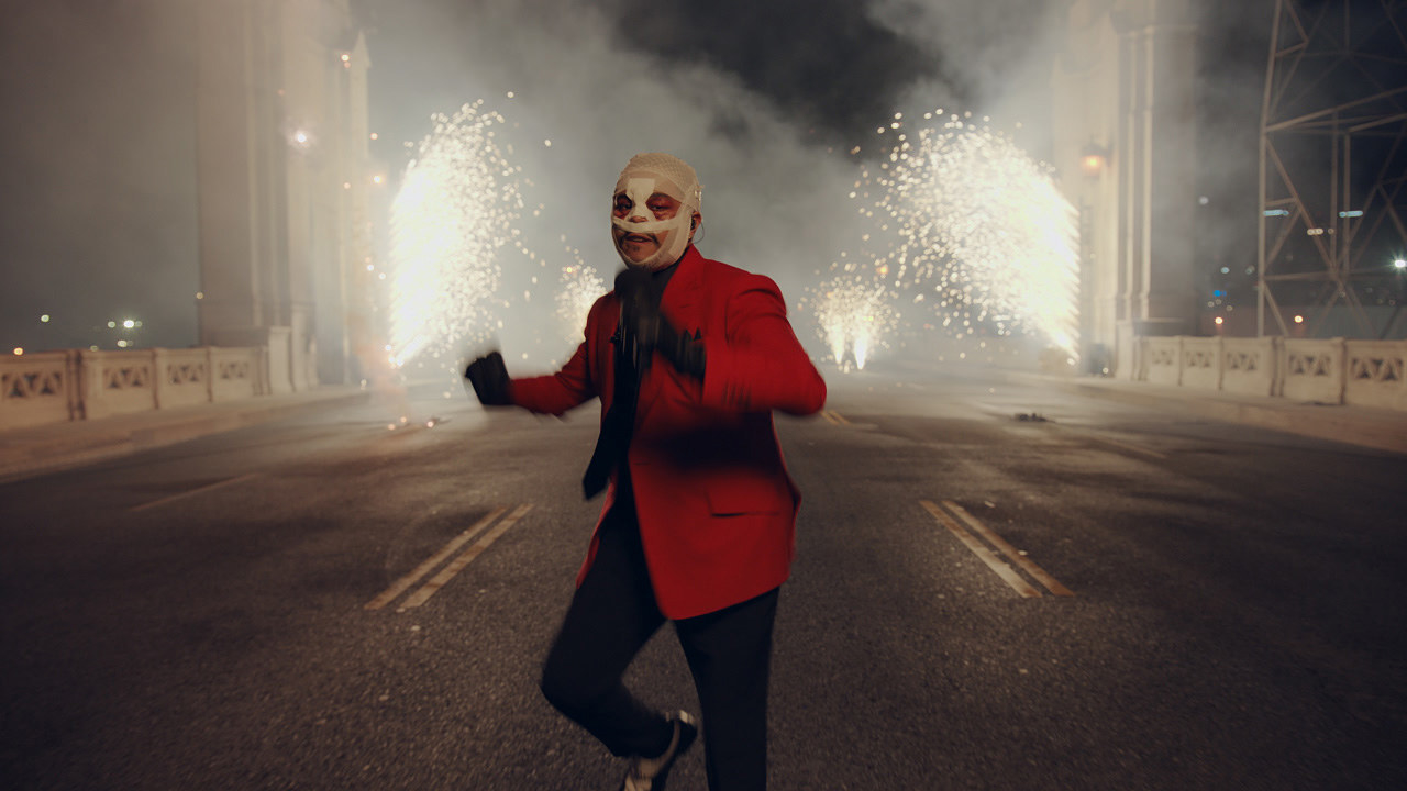 The Weeknd performs on a bridge with fireworks behind him at the 2020 American Music Awards