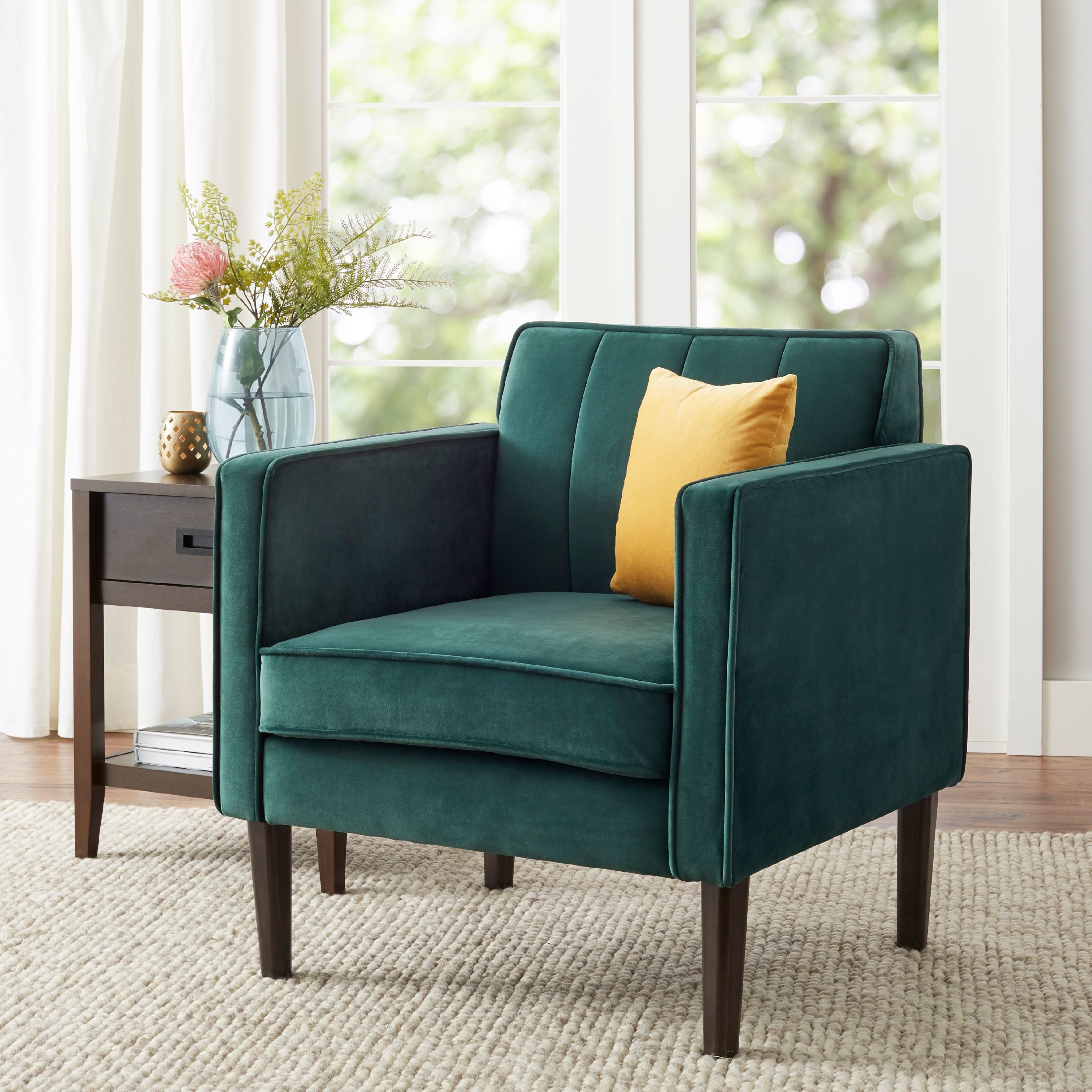 The chair, which has a vintage, midcentury look with a high square back and large square sidepiece armrests, in emerald