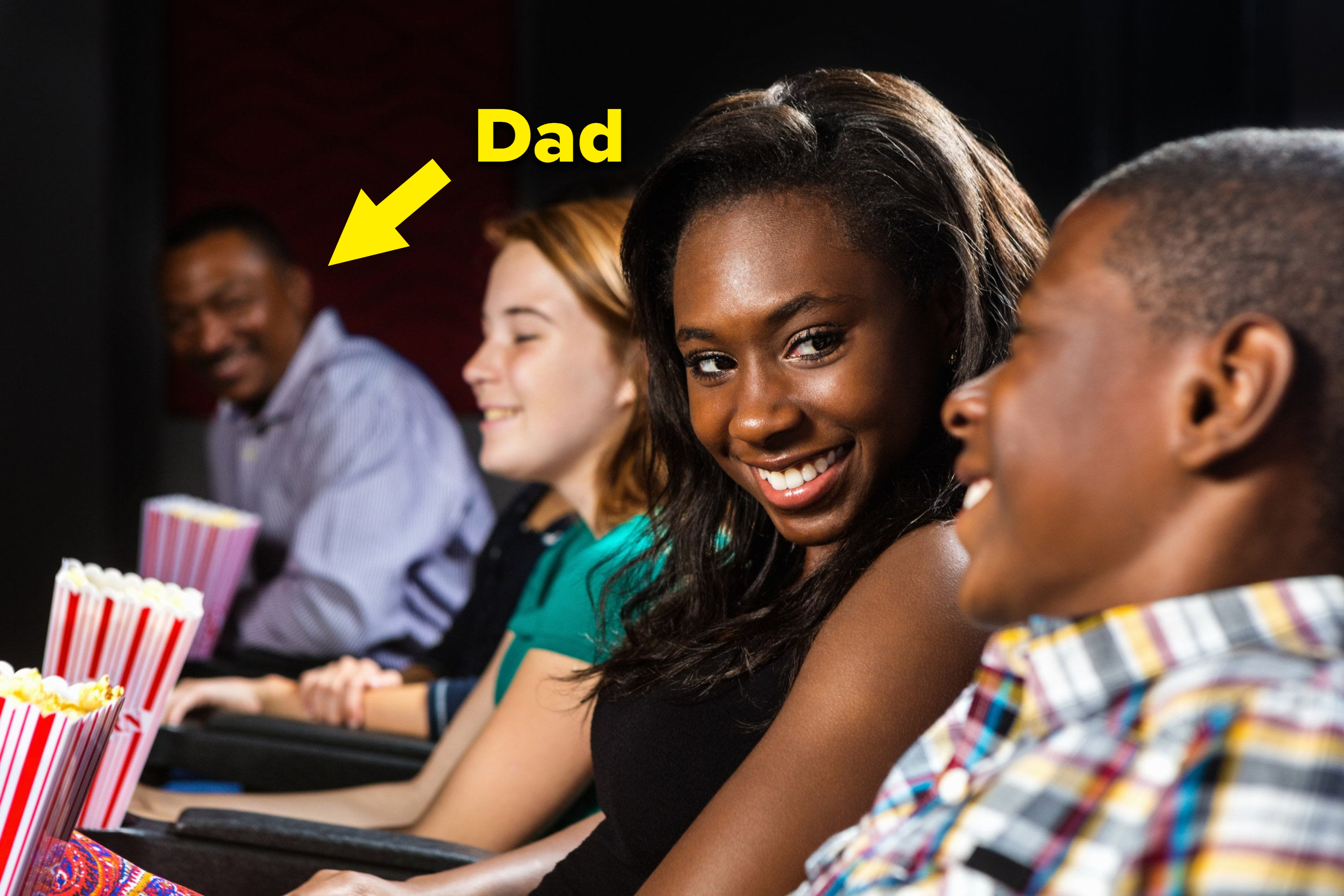 Two teens sit together in a movie as the girl&#x27;s dad looks on