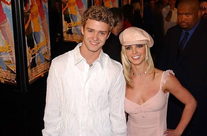 Justin and Britney posing on a red carpet with signs for her movie Crossroads in the background