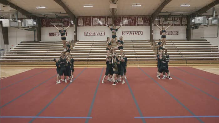 Three groups of cheerleaders in formation inside a gym