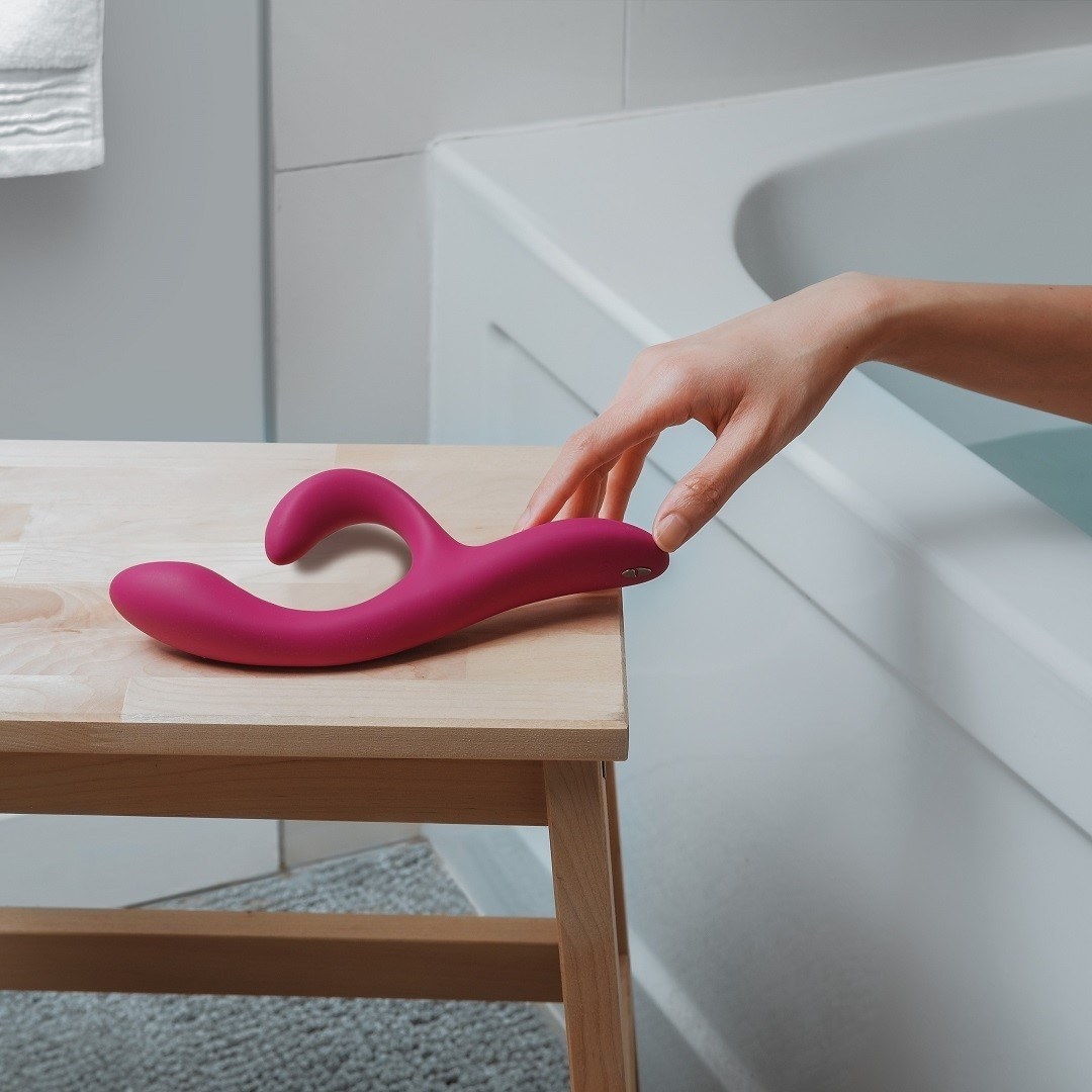 A person reaching for the vibrator beside a bath