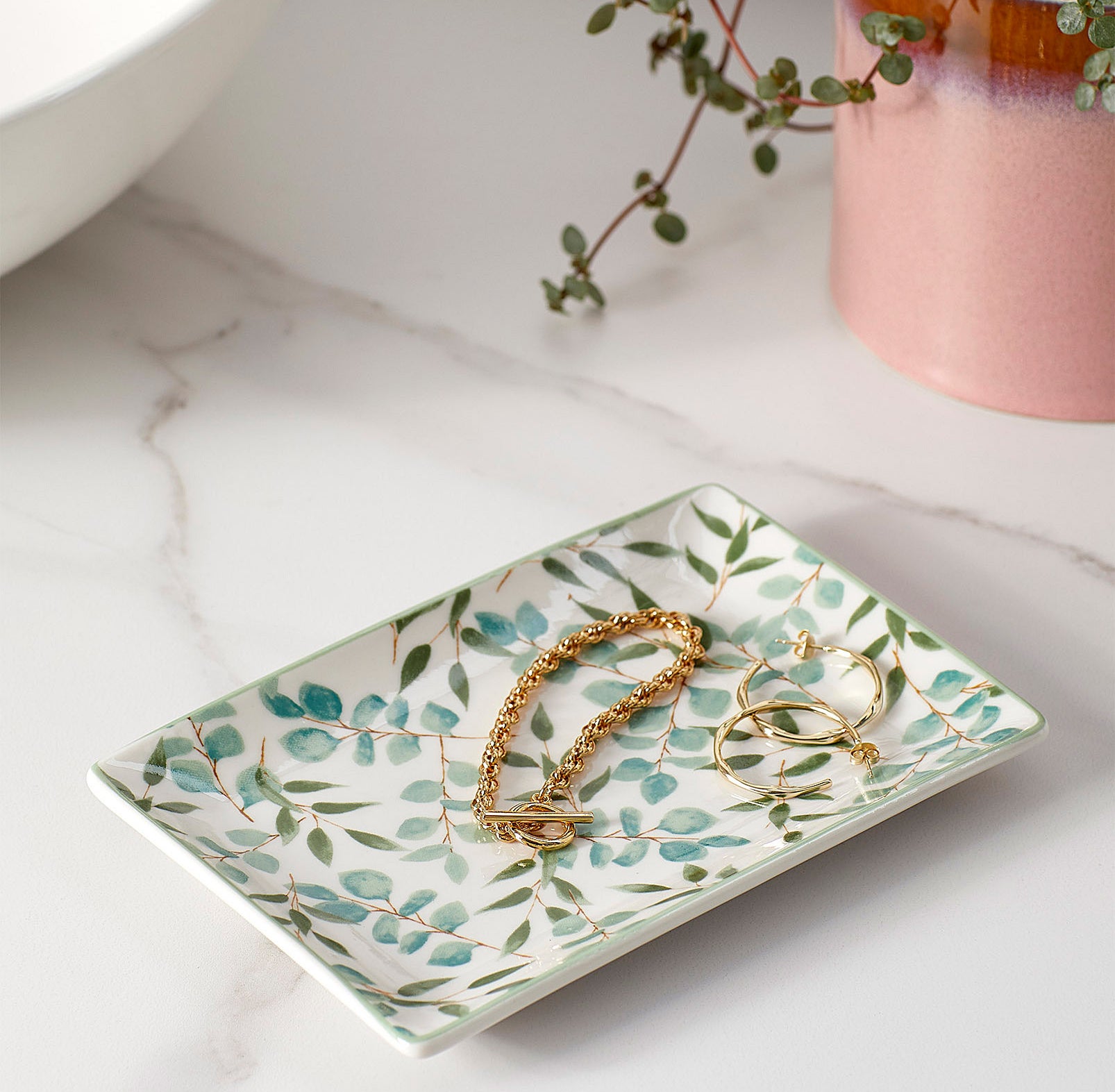 A cute patterned tray with jewelry on it 