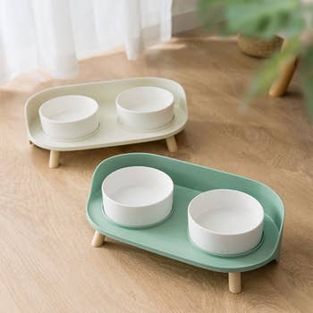 Two stands, one white and one mint green, with a high side and holding two white ceramic bowls